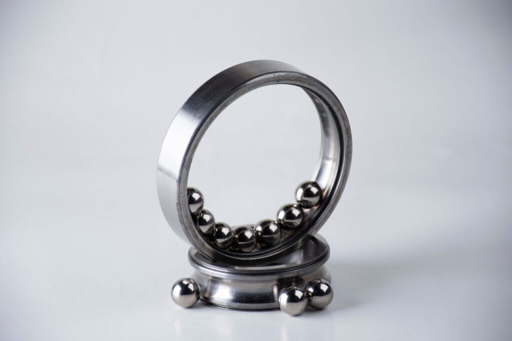 An artistic arrangement of a stainless steel ball bearing with silver balls on a clean white surface.